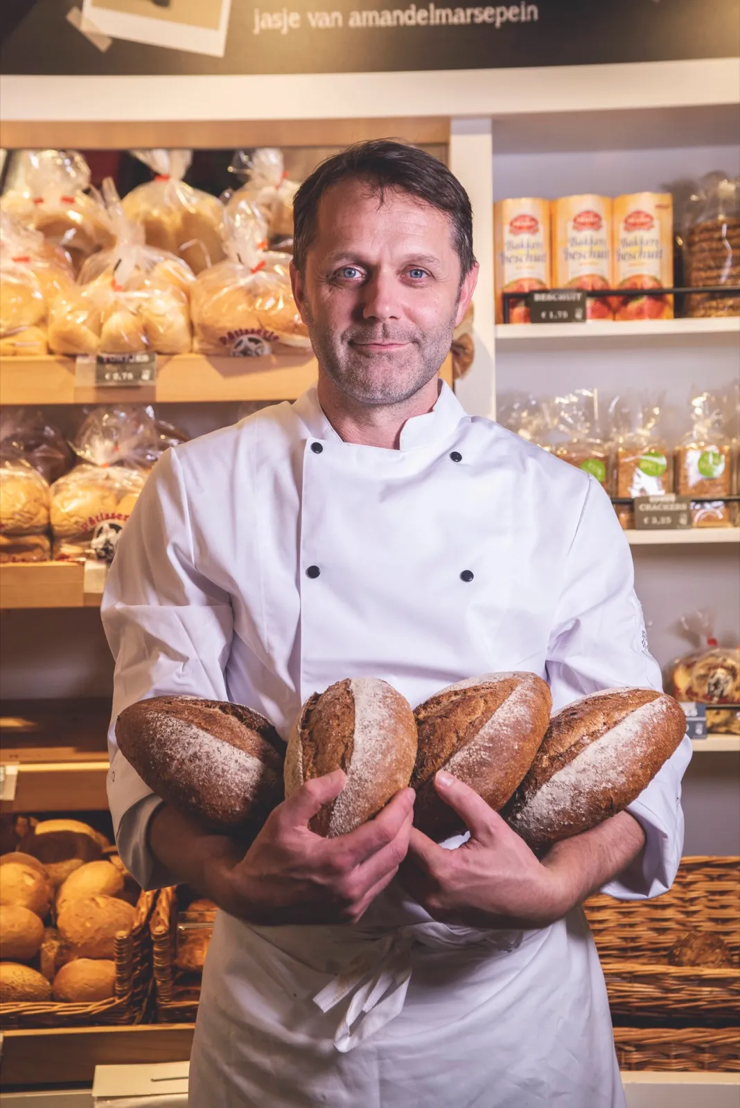 Bakker met versgebakken broden in de winkel